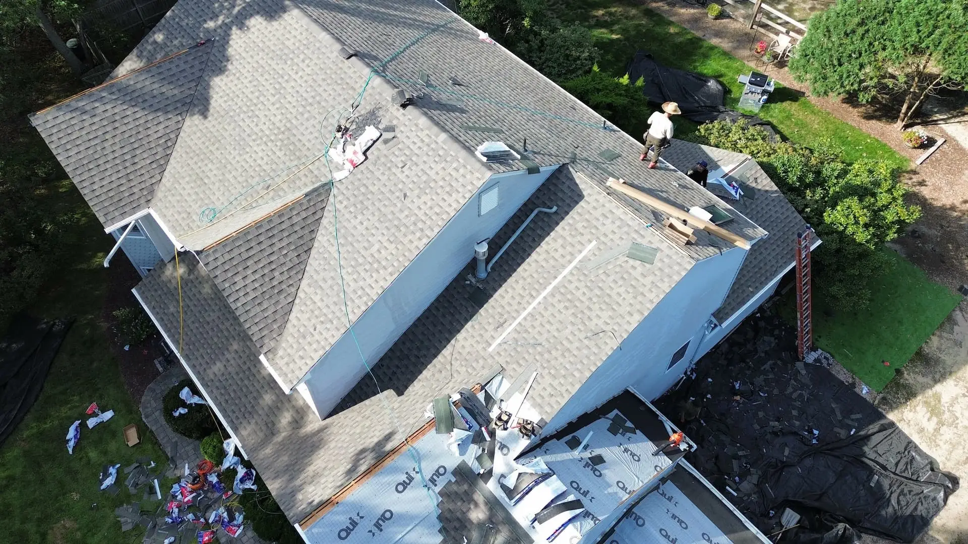 Aerial view of a roof replacement near completion, with crew members setting the final courses