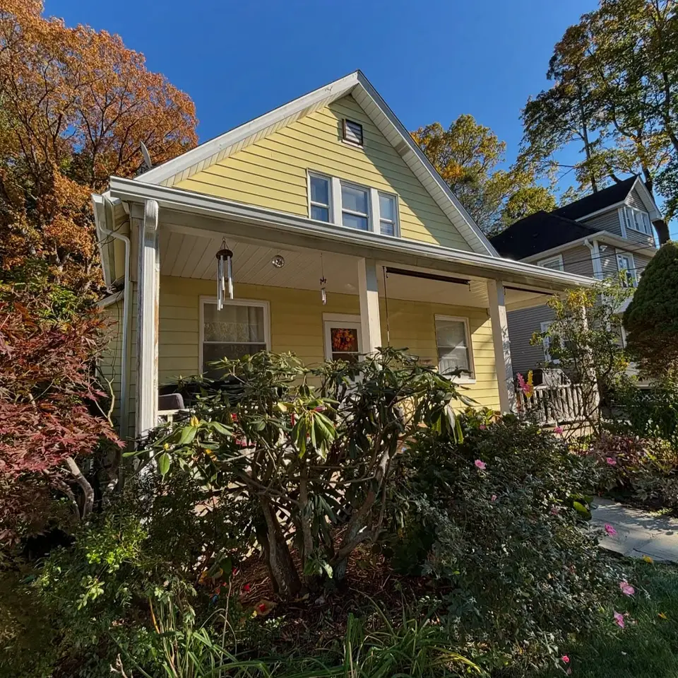 Yellow house with a front porch, white gutters along the porch roof and the main eave, and a downspout at the porch corner