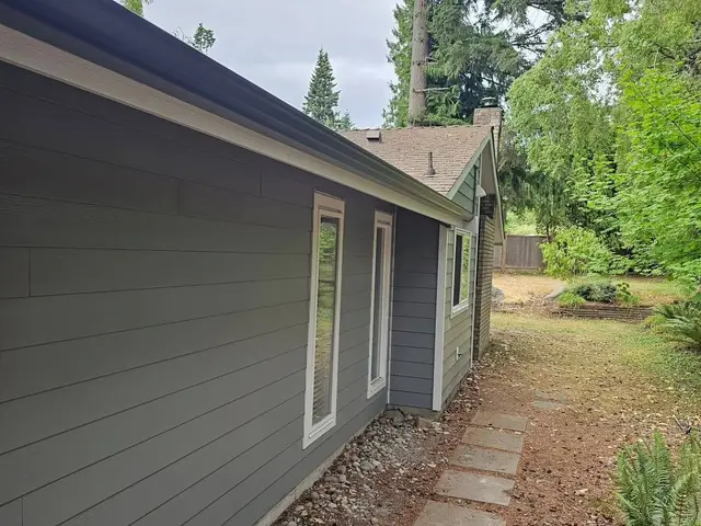 Lap siding running the length of a house wall with white trimmed windows, and new fascia and gutter along the eave above
